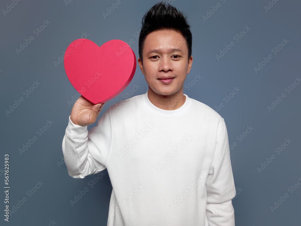 Handsome man showing red heart shape isolated on plain background Handsome man showing red heart shape isolated on plain background