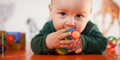 Cute baby boy nibbles and eats colourful toys because her small new teeth grow. Playground for babies