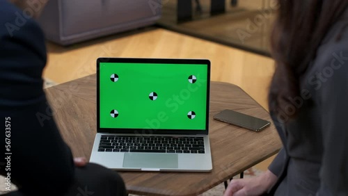 Shooting in the office. A man and a woman take turns pointing gestures at the laptop monitor. Colleagues in suits are actively discussing the project. Business meeting offline. Close-up, green screen.