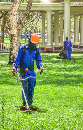african man , contractor, with a trimmer cutting grass