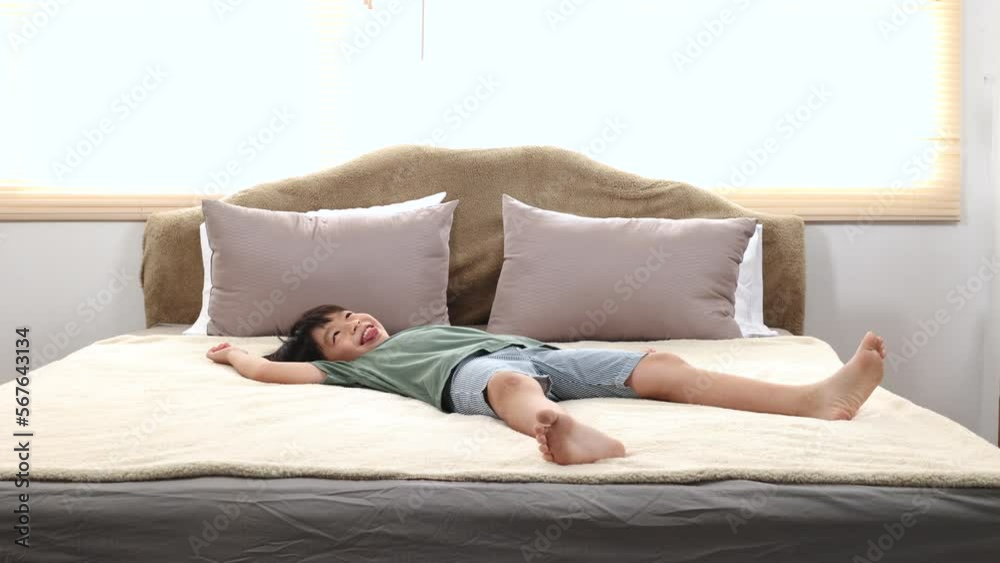 Happy asian elementary school boy jumping on bed and having fun, kid jump on bed switch legs back and forth funny dancing, adorable boy lifestyle happy holiday at home Happy asian elementary school boy jumping on bed and having fun, kid jump on bed switch legs back and forth funny dancing, adorable boy lifestyle happy holiday at home