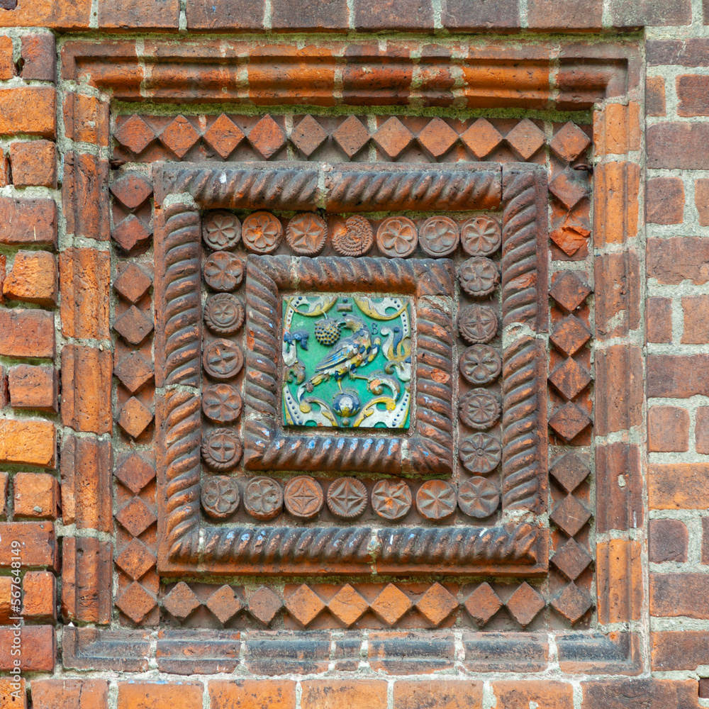 Fragment of decoration of an old brick church with a ceramic pattern