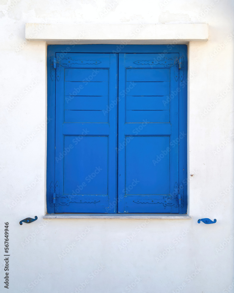 Bright blue painted window shutters on a white washed wall. Travel in Greek islands.