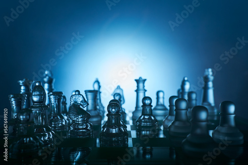Transparent chess figures on a chess board in dark surroundings. 