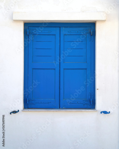 Bright blue painted window shutters on a white washed wall. Travel in Greek islands. © Dimitrios