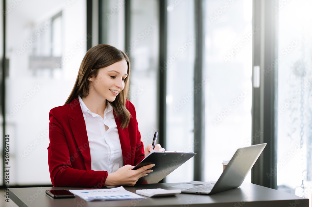 Young attractive Asian woman smiling thinking planning writing in notebook, tablet and laptop working at office