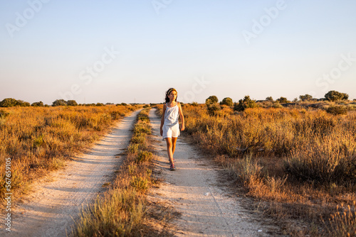 Lonely girl walking on a country road at sunset.