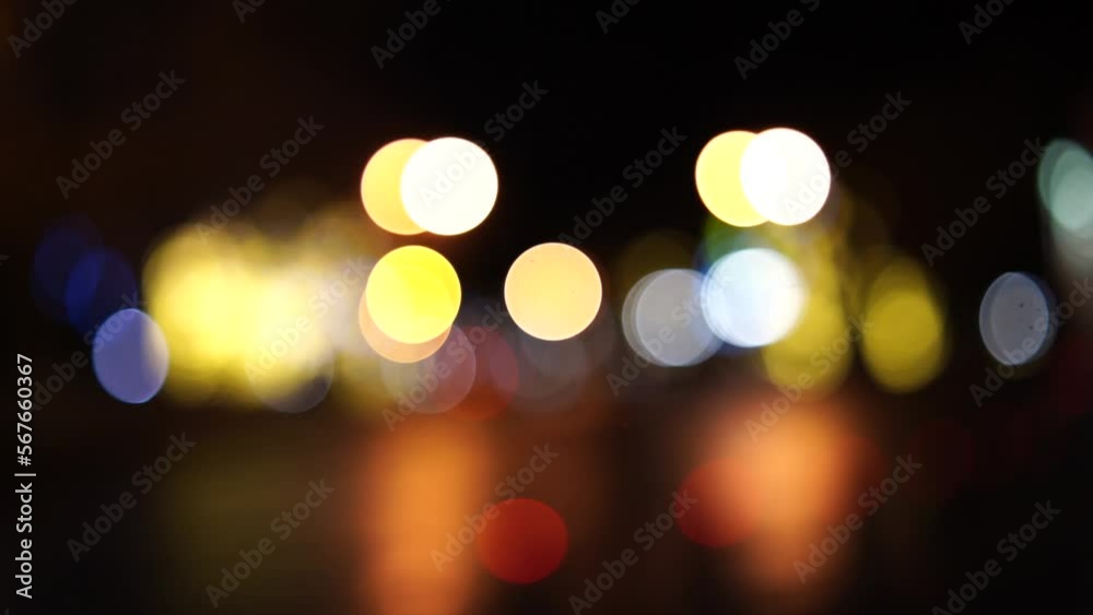 Blurred car lights bokeh in the evening city. Defocused headlights and street lighting at night. Moving bokeh circles of cars at night. Blurred city traffic background Blurred car lights bokeh in the evening city. Defocused headlights and street lighting at night. Moving bokeh circles of cars at night. Blurred city traffic background