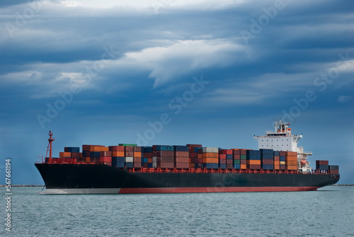 Nave mercantile porta container, ormeggiata al largo di un porto del Mediterraneo, il cielo è minaccioso photo