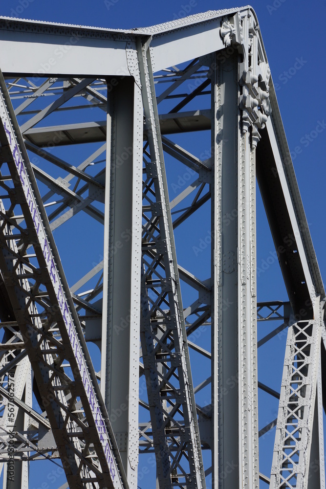 Fachwerk-Tragekonstruktion einer Stahlbrücke aus den 1920er-Jahren. Teleobjektiv-Zoom, vor wolkenlosem blauem Himmel. 