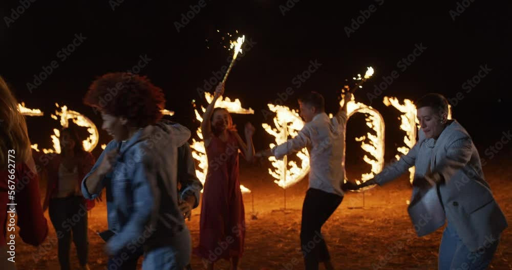 Group of Young, Carefree, Happy Multi-ethnic Friends Having Fun, Jumping and Dancing with sparklers and a Background of Pyrotechnic Fire Letters Spelling FREEDOM. Energetic Youth Celebrating Life Group of Young, Carefree, Happy Multi-ethnic Friends Having Fun, Jumping and Dancing with sparklers and a Background of Pyrotechnic Fire Letters Spelling FREEDOM. Energetic Youth Celebrating Life