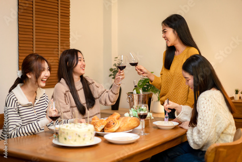 Young smiling woman drinking and clinking glass of wine to toasting with happiness while celebrating in new year party at home