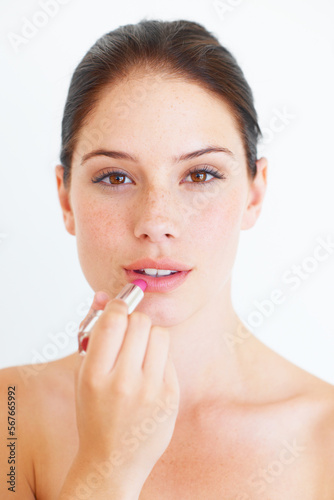 Woman, face and portrait with lipstick for makeup, cosmetics or skincare isolated against a white studio background. Beautiful happy female applying cosmetic product on lips for beauty in self love