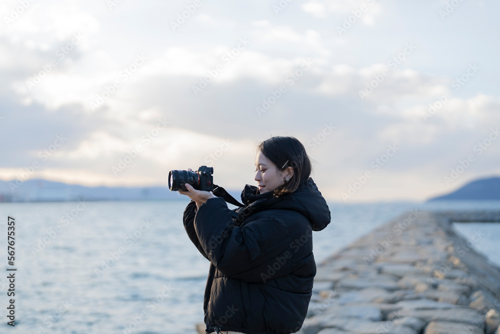 Obraz premium 夕暮れの海で写真を撮る女性