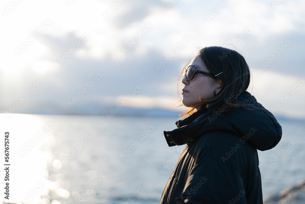 夕暮れの海でサングラスをしている女性 夕暮れの海でサングラスをしている女性