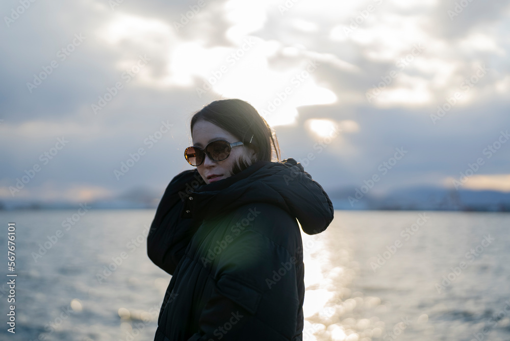 Obraz premium 夕暮れの海でサングラスをしている女性