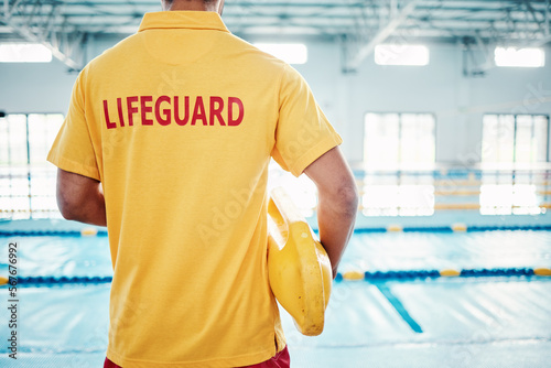 Security, safety or lifeguard by a swimming pool to help rescue the public from danger or drowning in water. Back view, trust or man standing with a lifebuoy ready with reliable assistance or support photo