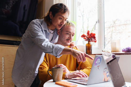 фотографія Loving Same Sex Male Couple In Lounge Sitting At Home Looking At Laptop Together