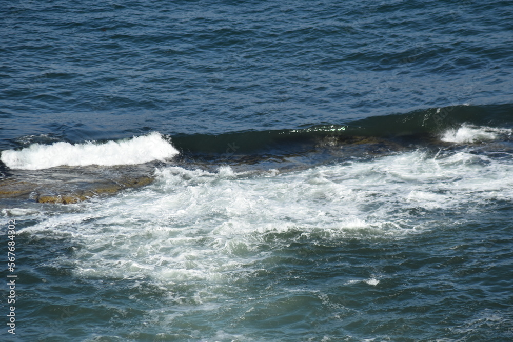 Aerial view looking down onto waves crashing onto rocks. North Berwick Scotland. 