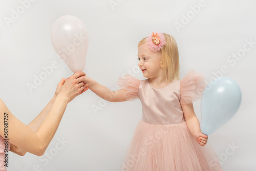 Beautiful girl in lush pink dress smiling takes balloon from hands of woman. Little blonde princess isolated on white background © somemeans