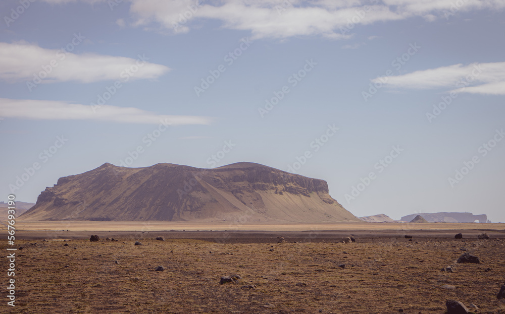 A towering hill stands proud, a beacon of natural strength amidst the rolling, verdant planes of Iceland