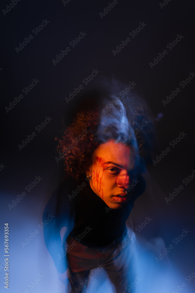 double exposure of african american man with bipolar disorder and bleeding face looking at camera on black with orange and blue light double exposure of african american man with bipolar disorder and bleeding face looking at camera on black with orange and blue light