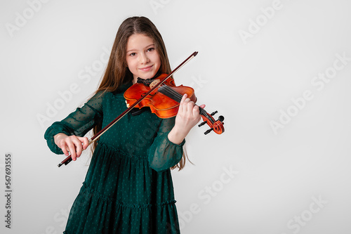 A girl in a green dress plays the violin on a white background.