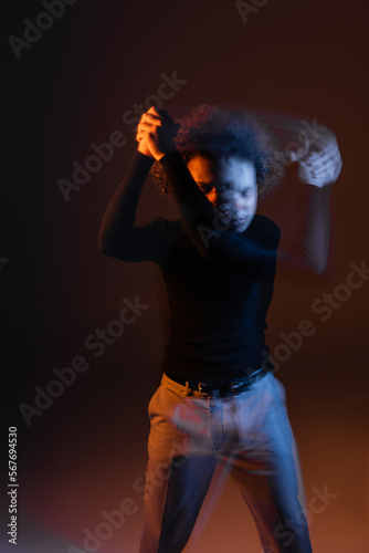 long exposure of wounded african american man with bipolar disorder on dark background with orange and blue light