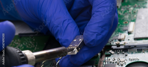 working hands in blue gloves, repairing the electrical circuit, soldered by a slot for charging