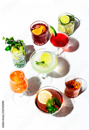 Most popular trendy cocktails set: aperol spritz, negroni, mojito, gin tonic and cosmopolitan, daiquiri, margarita and old fashioned on white background, top view. Hard light and harsh shadow