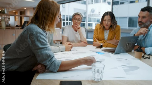 Creative business people having a meeting in an office, sitting around a table discussing a set of blueprints. Group of design architects collaborating on a project, brainstorming ideas as a team.