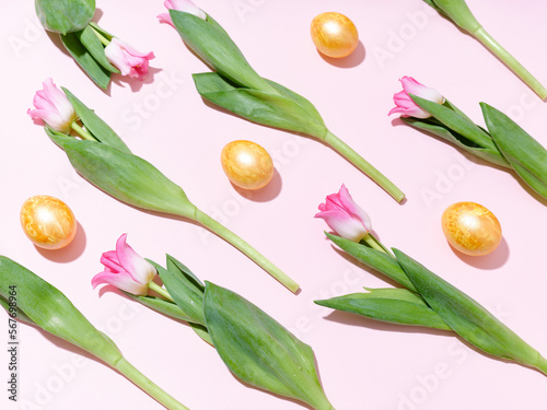 Flatlay with a pattern of golden easter eggs and tulips on pink background