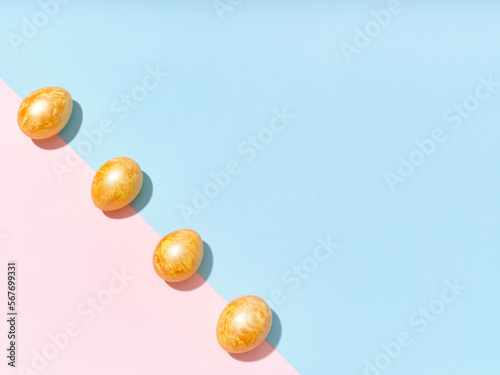 Creative layout with colored golden easter eggs on bright blue and pink background. Festive imagery concept