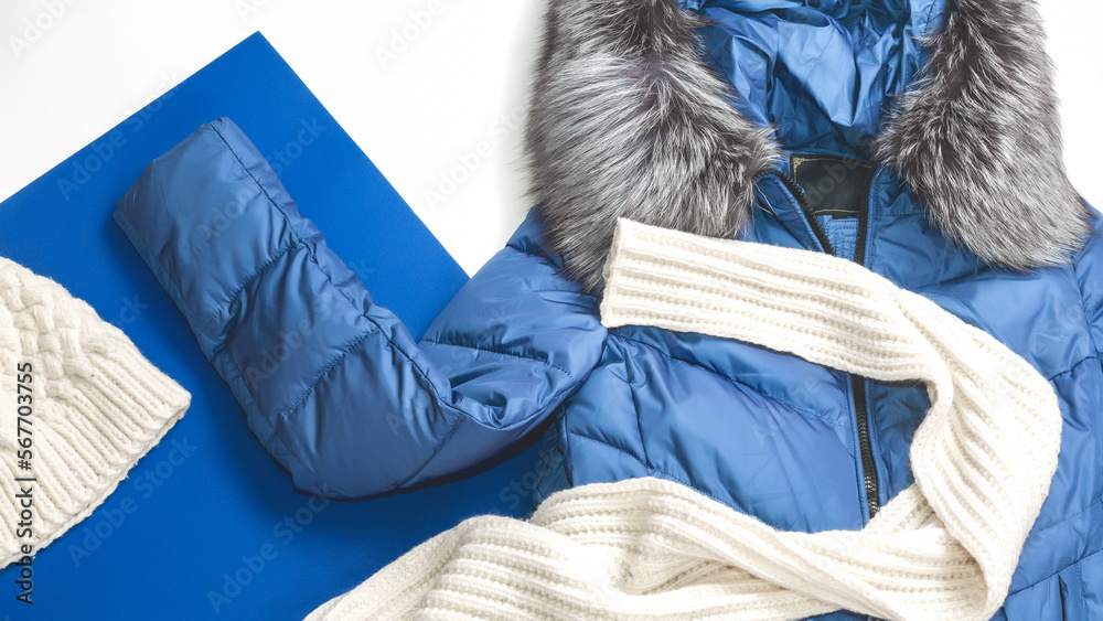 warm winter knit scarf on blue jacket. Fashionable warm winter background. Blue Down jacket with fur collar hood.