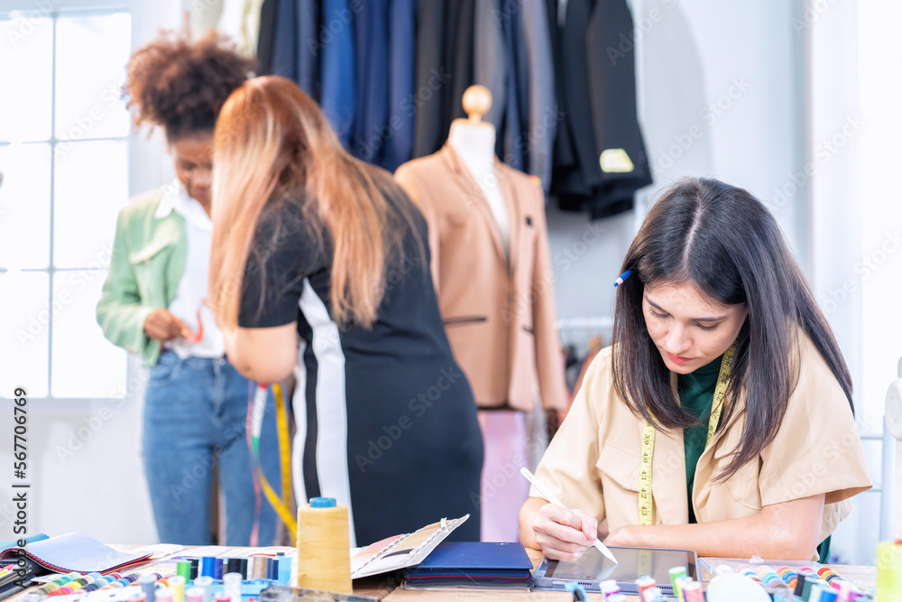 Fototapeta premium Attractive Young Asian woman professional fashion designer checking finished cloth in studio room