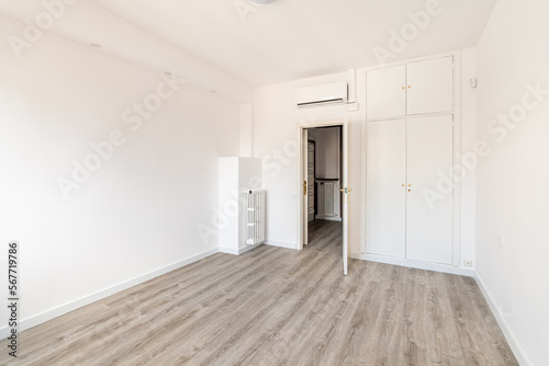 An empty spacious room for a bedroom  with a closet built into the wall  an air conditioner above the front door and a radiator on the wall to create heat during the cold season. Eco wood floor.