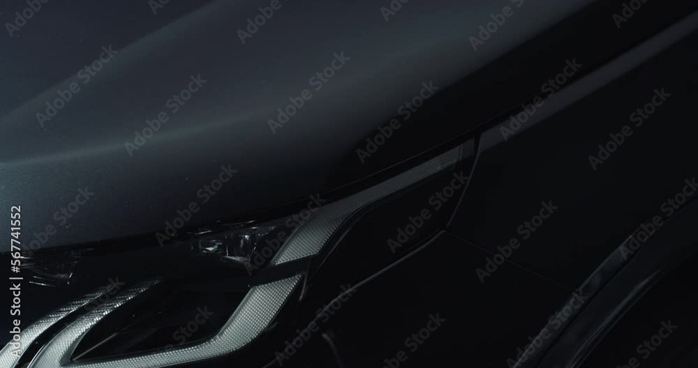 Aesthetic Close Up of the Headlight of a Black Anonymous Luxurious Car. Light Turned On Slowly Reveals the Details of a Modern Prestigious Vehicle's Design. Concept of Car Adds and Dealership Aesthetic Close Up of the Headlight of a Black Anonymous Luxurious Car. Light Turned On Slowly Reveals the Details of a Modern Prestigious Vehicle's Design. Concept of Car Adds and Dealership