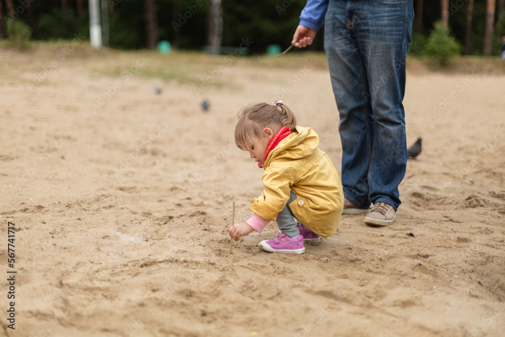 Little girl drawing on sand with her father Little girl drawing on sand with her father