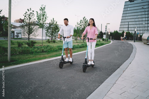 Happy couple riding kick scooters in city