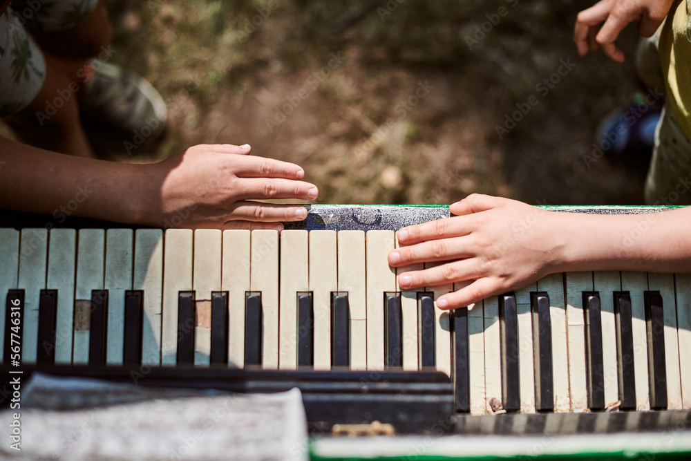 Two little boys hands playing on piano keyboard above view close up,  children pampering art hobby play music with outdoor art piano. Musical  hobby of little boy playing piano, music performance foto