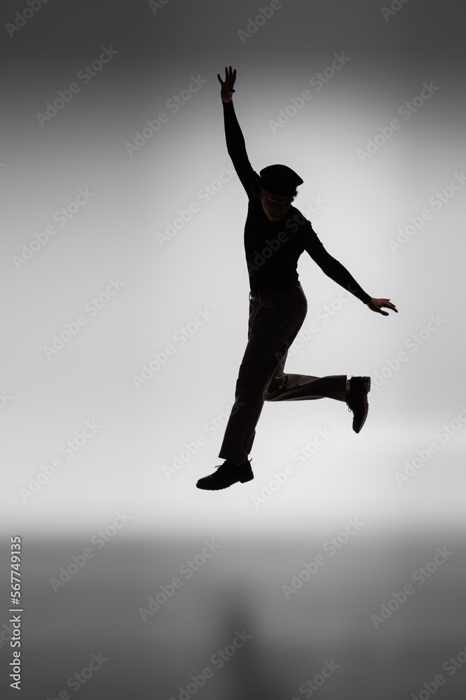 dark silhouette of young african american man jumping on grey background