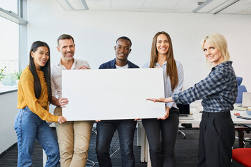 Group of diverse casual business people standing in office holding big blank banner