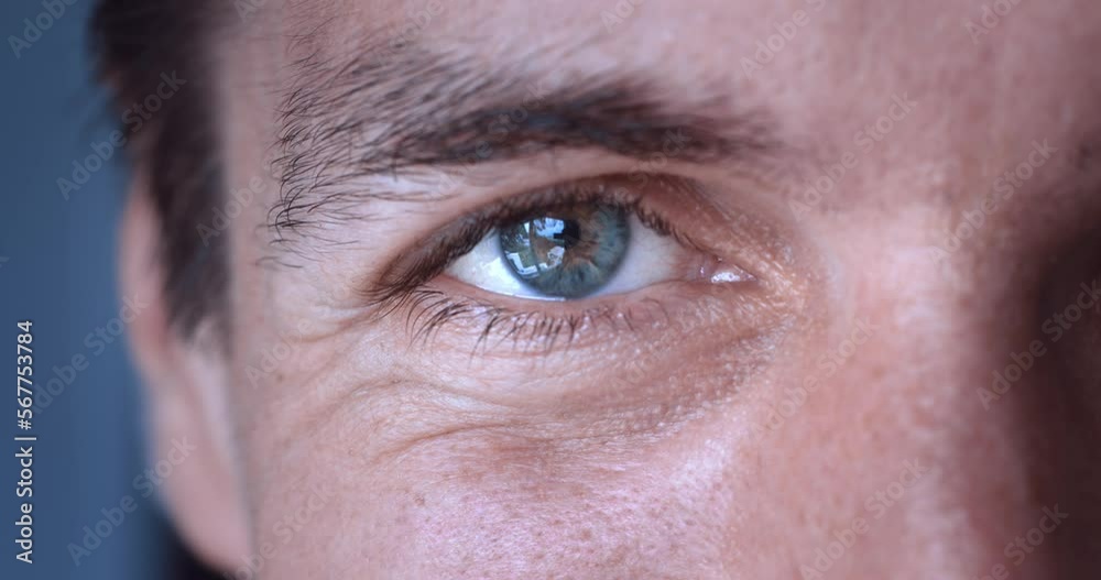 Close-up of the grey eye of millennial male in his 30s smile. Close up male eye looking into the camera and smiling. Eye macro, vision concert Close-up of the grey eye of millennial male in his 30s smile. Close up male eye looking into the camera and smiling. Eye macro, vision concert