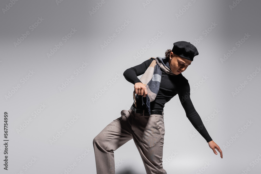 trendy african american man in black beret and plaid scarf posing on grey background trendy african american man in black beret and plaid scarf posing on grey background