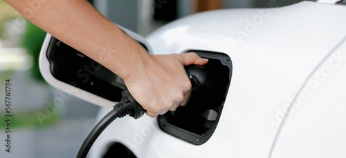 Progressive concept of hand insert an emission-free power connector to the battery of electric vehicle at home. Electric vehicle charging via cable from charging station to EV car battery