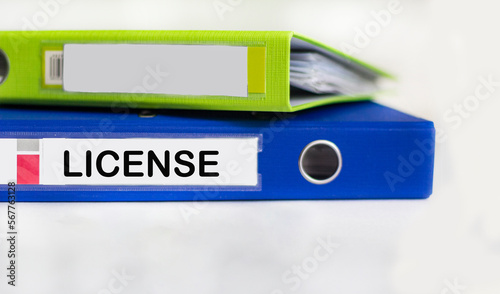 The word License is written on a blue folder and on a white background. the concept of giving a person the right to use something.