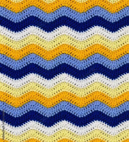 Seamless knitted pattern in the form of zigzags crocheted with threads of contrasting colors. Acrylic baby yarn. African style.