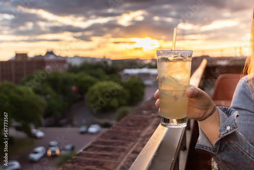 A hand holding a yellow alcoholic beverage margarita at a Savannah, Georgia at sunset