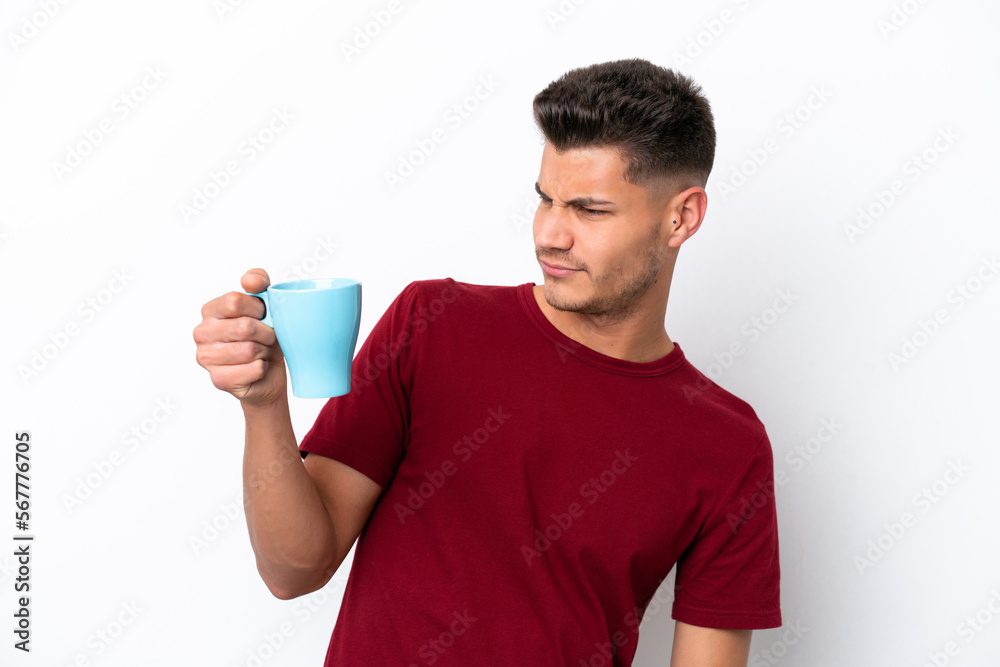 Young caucasian man holding cup of coffee isolated on white background with sad expression Young caucasian man holding cup of coffee isolated on white background with sad expression