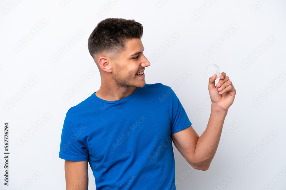 Young caucasian man holding invisible braces isolated on white background with happy expression Young caucasian man holding invisible braces isolated on white background with happy expression